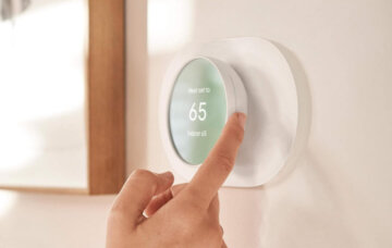 A person adjusts a Google Nest Thermostat