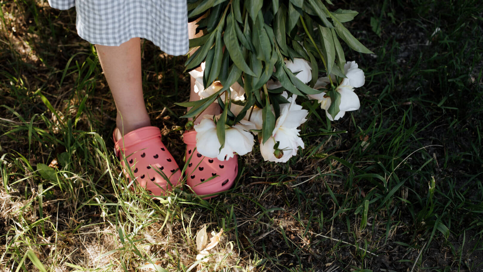Person wearing pink Crocs holds a bunch of flowers