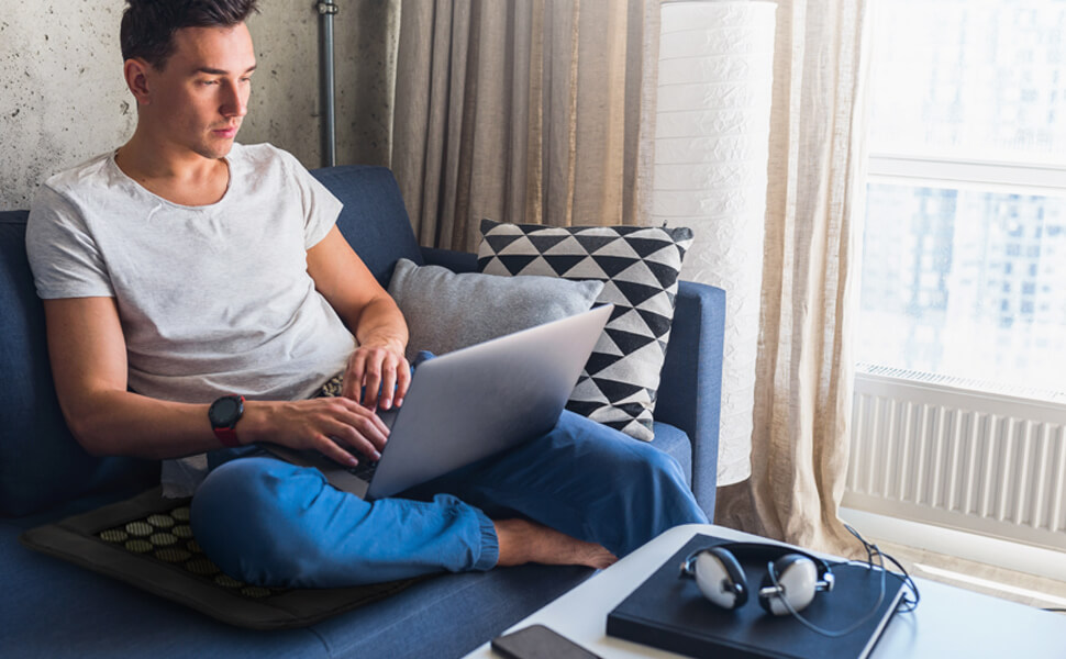 Image on man sitting on an Infrared heating pad while using a laptop - How to use a heating pad